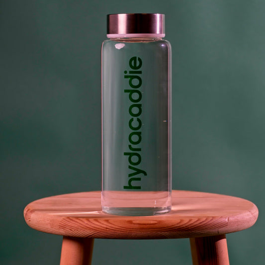 Product image for the hydracaddie lifestyle bottle. A premium glass bottle with stainless steel lid on a green background.