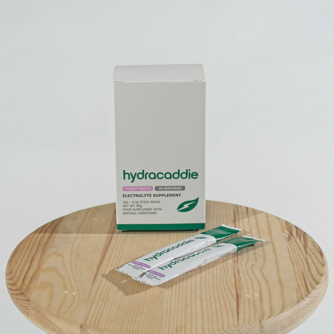 Box of hydracaddie forest fruits electrolyte supplement on a white background with a single stick sachet next to the box.
